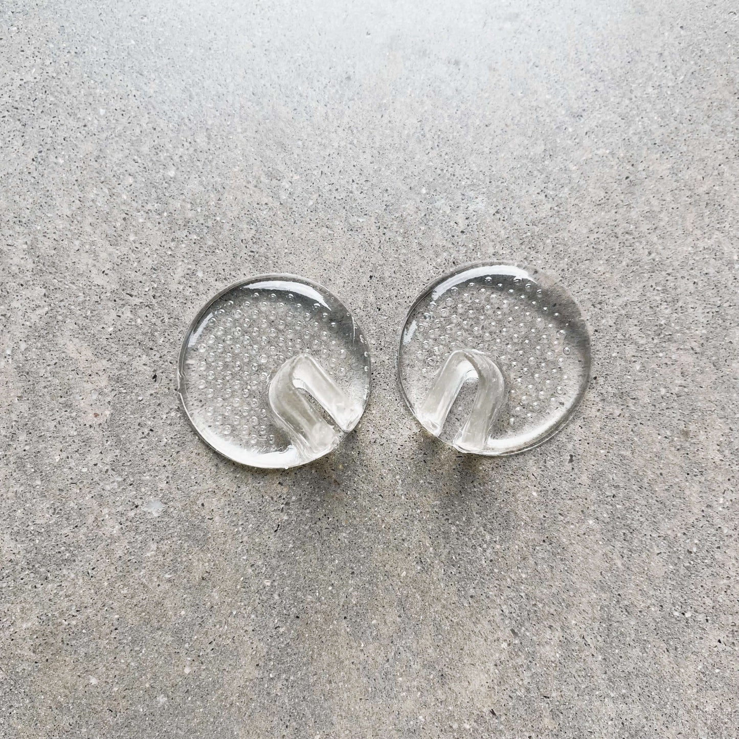 A pair of toe protectors are sitting side by side on a grey background.