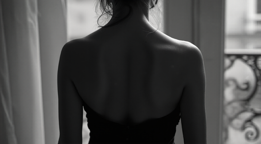 Black and white editorial photograph of a woman wearing an elegant strapless dress, classic monochrome lifestyle imagery.