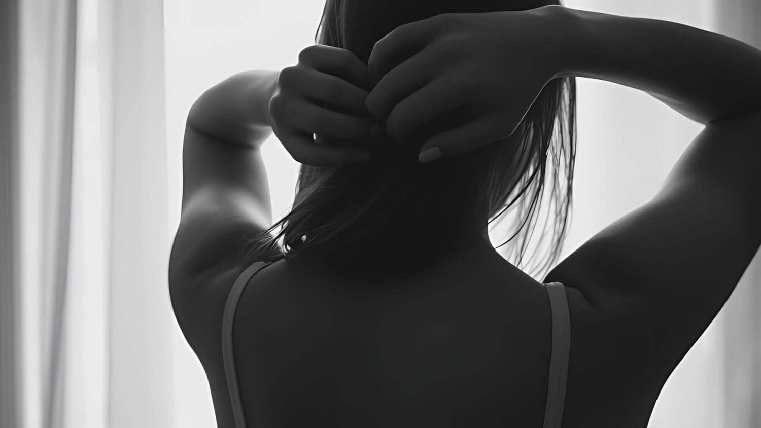a woman wearing a bra in front of a curtain behind a silhouette effect