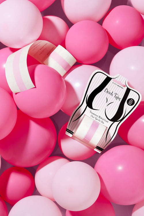 A packaging of Clear Boob Tape with the roll sitting amongst dark pink and light pink balloons.