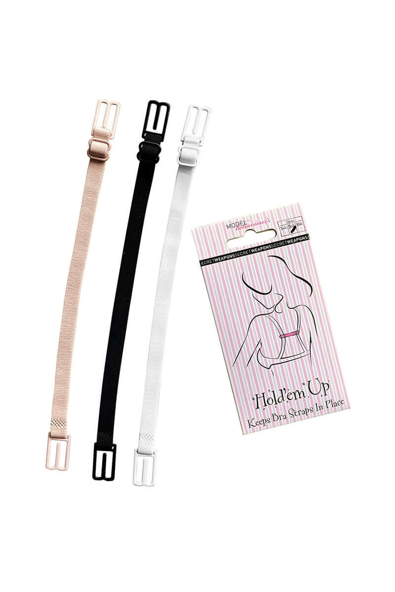 Three adjustable bra strap holders in beige, black, and white lie next to packaging. Text reads: "MODEL BEHAVIOUR, SECRET WEAPONS, Hold'em Up, Keeps Bra Straps In Place."