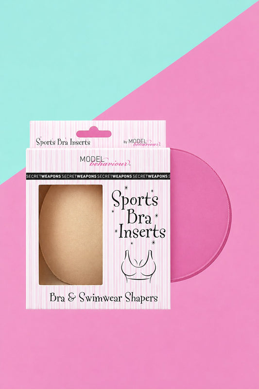 A pair of beige skin colour Sports Bra Inserts inside Secret Weapons branded pink and white retail box packaging on a pink and light aqua background