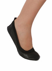 Black foldable ballets flat shoe on the foot of a woman against a white background.