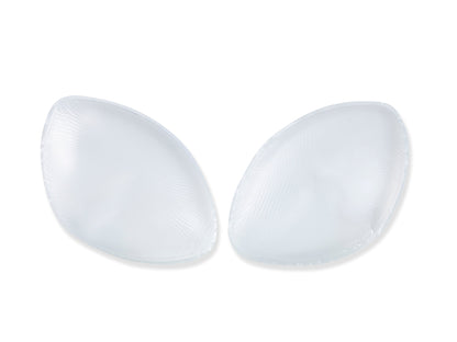 Two transparent silicone pads rest against a plain white background, appearing smooth and slightly convex, typically used for cushioning or support in garments or shoes.