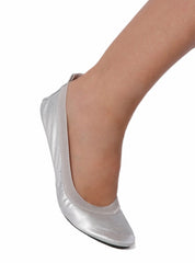 Silver foldable ballets flat shoe on the foot of a woman against a white background.